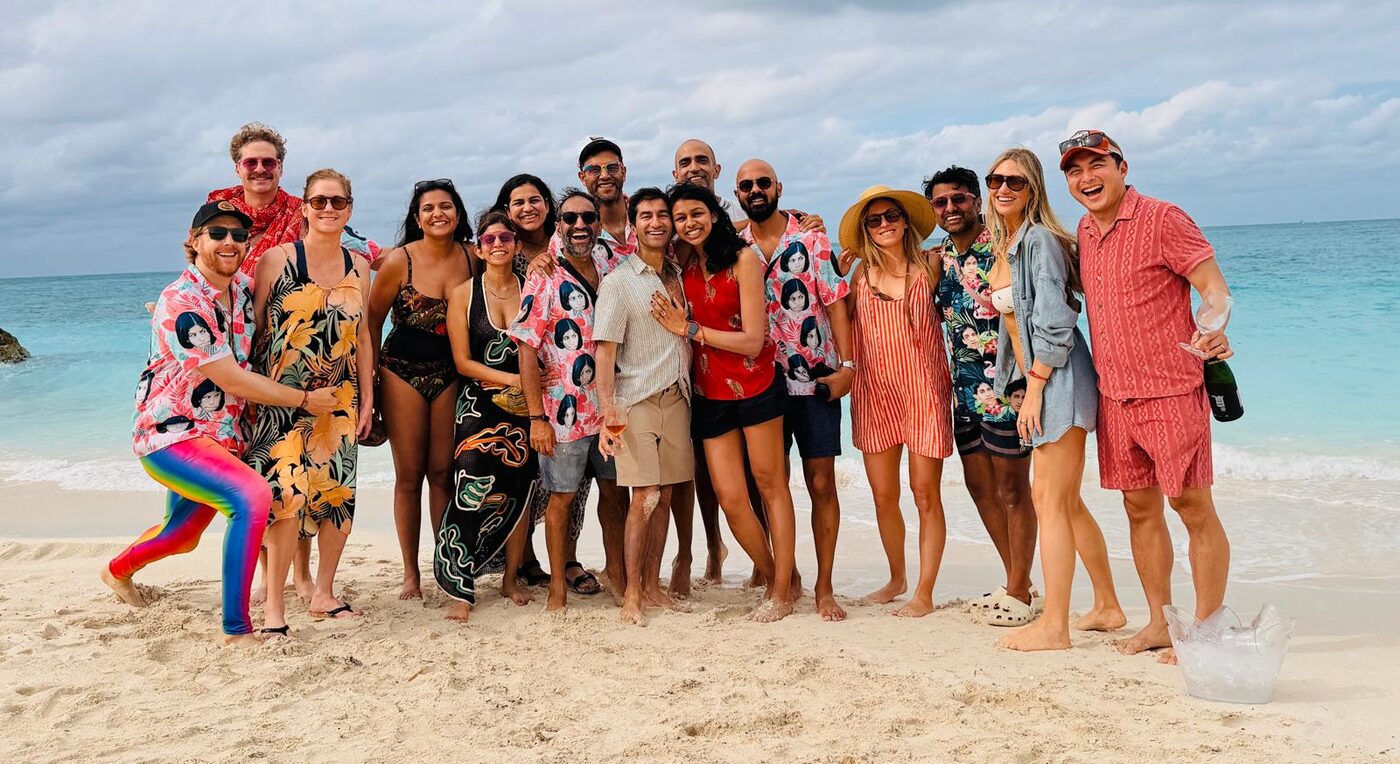Rishi and Esha celebrating on the beach in Bimini, Bahamas, surrounded by friends